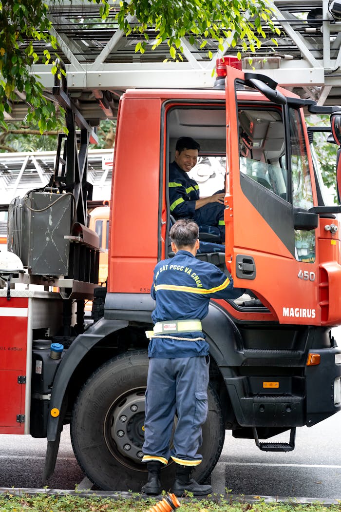 Firefighters conversing by a Magirus fire truck during a rescue operation.
