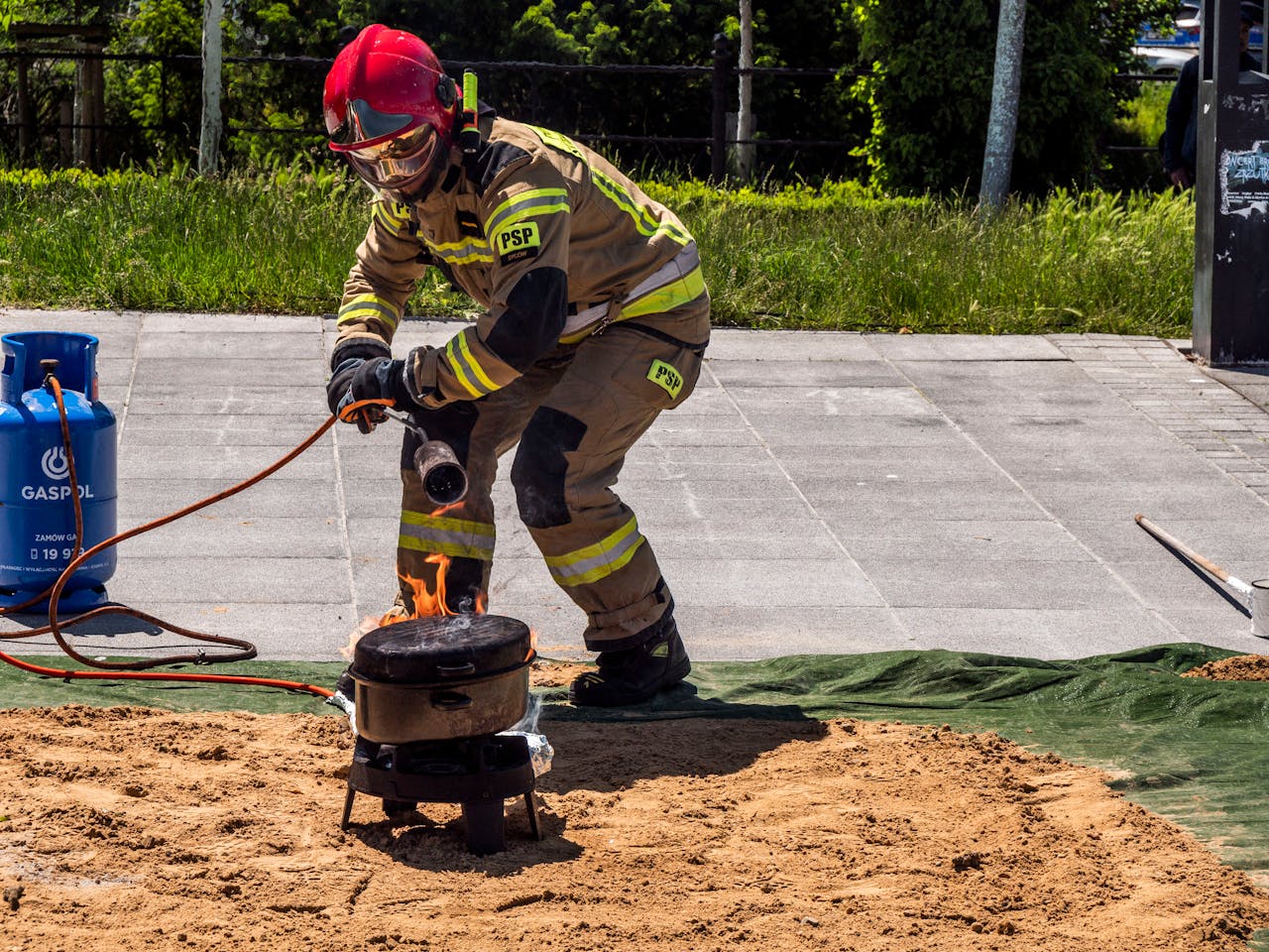 A firefighter safely ignites a controlled fire for a demonstration outdoors.